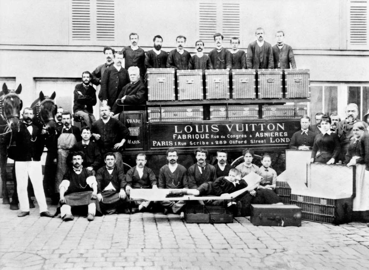 Louis Vuitton in a bed trunk’s driver seat with family & workshop members, circa 1888